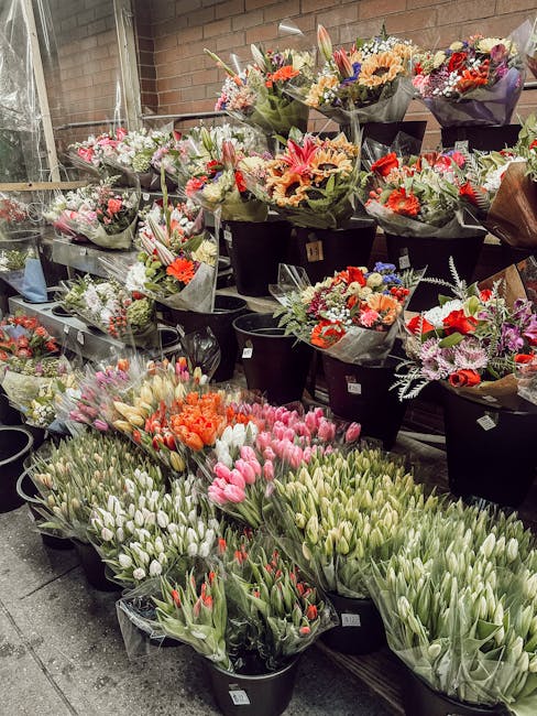 A variety of fresh flower bouquets and potted floral arrangements displayed outside a flower shop on Station Road, featuring an assortment of colorful blooms such as pink and white tulips, orange lili